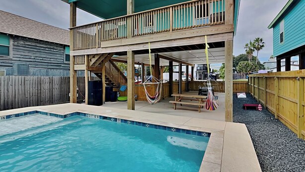 A two-story house with a backyard pool, wooden deck, and a covered patio area. - Marlin Manor by Silver Sands Vacation Rentals (Port Aransas)