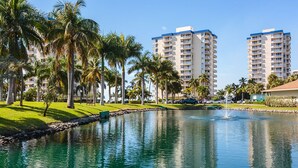 Un hôtel situé au bord de l’eau, doté d’une piscine, de palmiers et dont l’arrière-plan est constitué d’immeubles de grande hauteur.