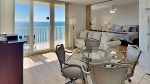 Une chambre moderne avec une table en verre entourée de chaises, d’un canapé et d’un lit.