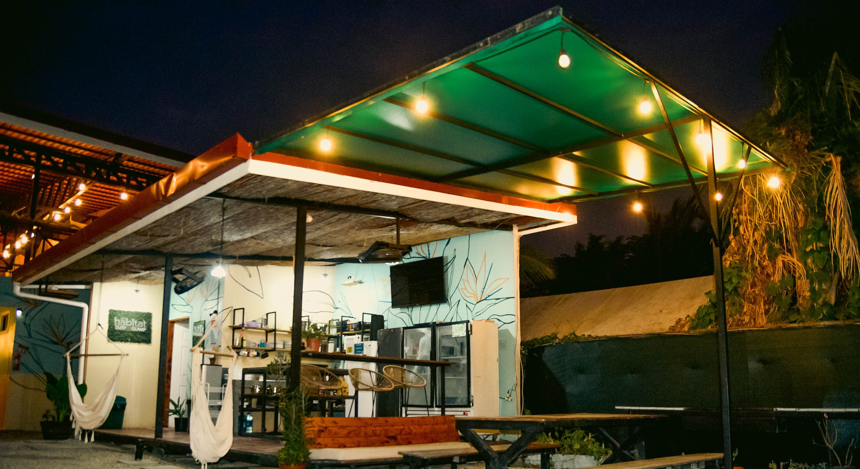 Un área de comedor al aire libre con un espacio de estar techado, mesas y sillas.