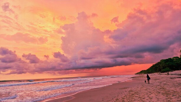 A beach with waves, a sunset, and a few people. - Habitat Surf Glamp (Cóbano)