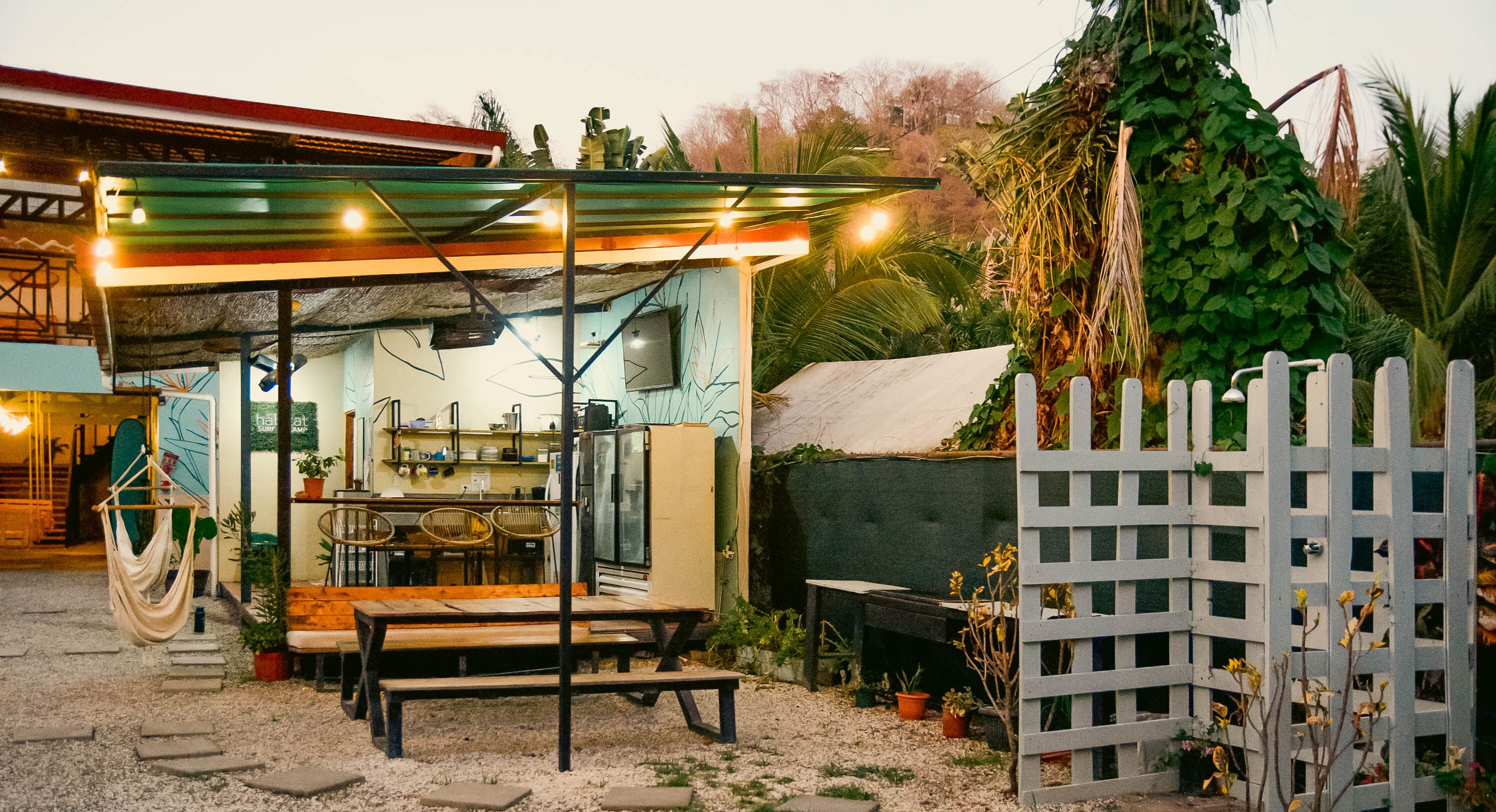 Un espace extérieur accueillant avec une table et des chaises, un fauteuil suspendu et un patio couvert.
