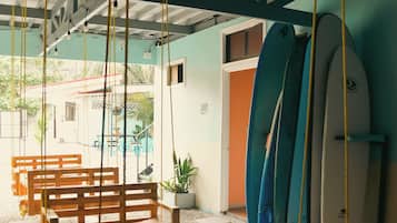 A beachside seating area with wooden benches and surfboards against the wall.