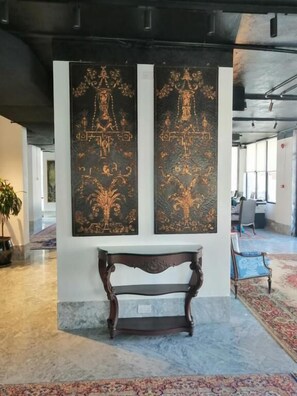 A lobby with a bench, two wall-mounted artworks, and a patterned carpet. - Kuwait Residence (Kuwait City)