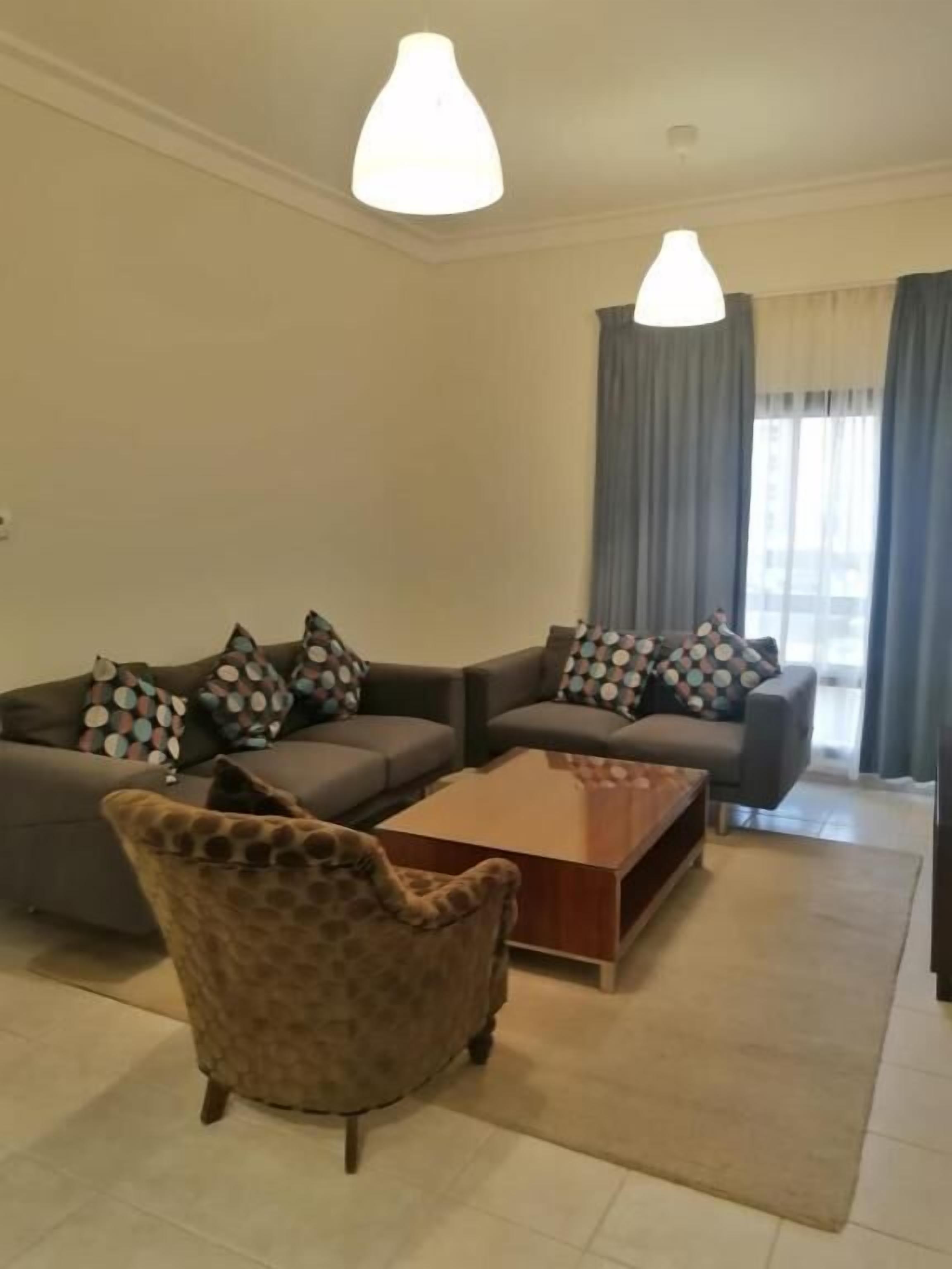Una sala de estar con un conjunto de sofá, un sillón estampado y una mesa de centro.