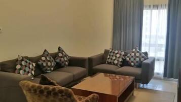 Una sala de estar con un conjunto de sofá, un sillón estampado y una mesa de centro.