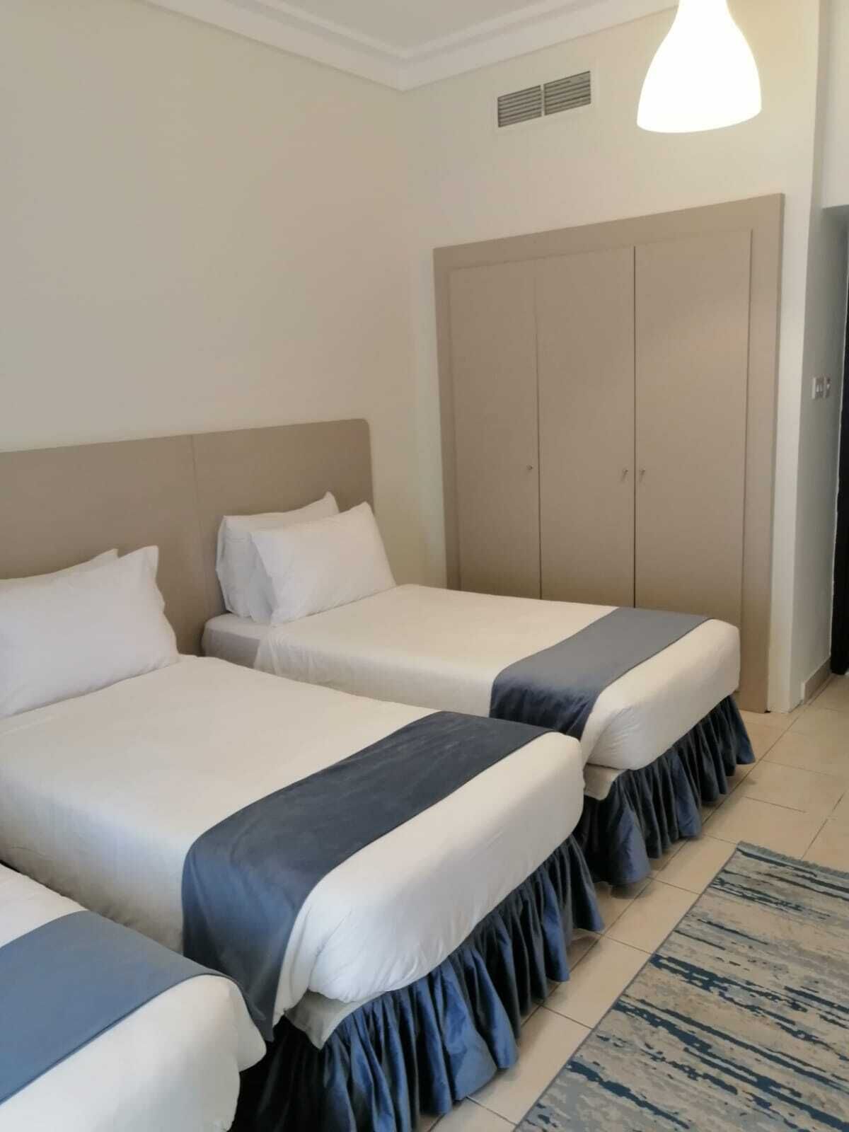 A hotel room with two beds, a wardrobe, and a ceiling vent.