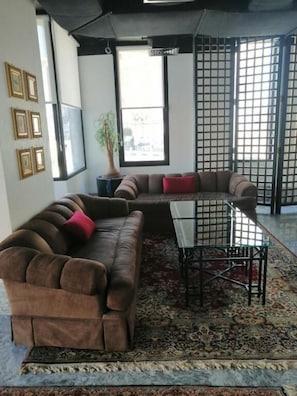 A living room with a sectional sofa, a glass coffee table, and a patterned rug.