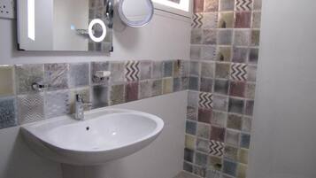 A bathroom with a white sink, a mirror, and a wall with multicolored tiles.