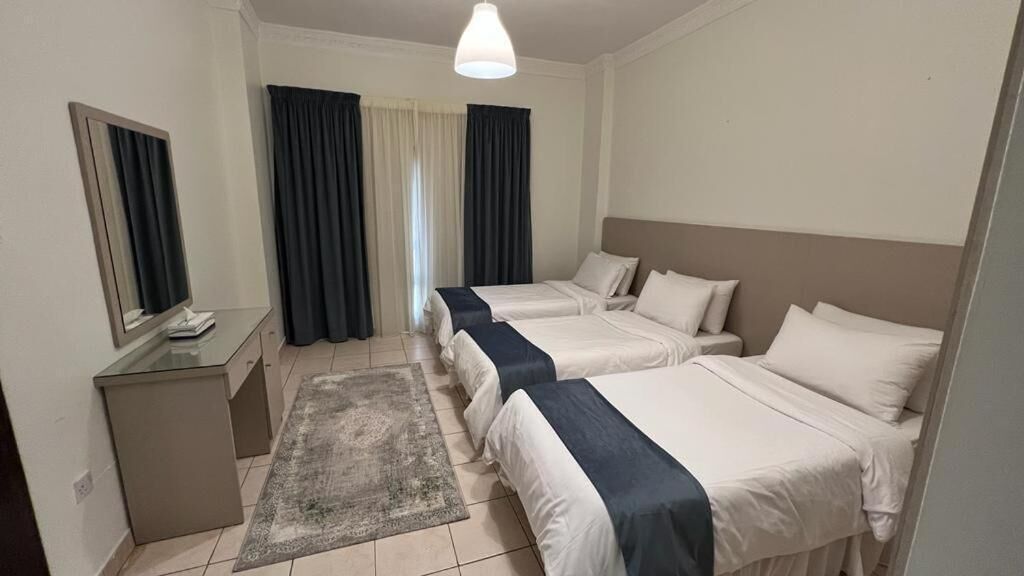 A hotel room with two beds, a desk with a mirror, and a small rug.