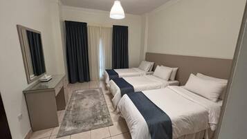 A hotel room with two beds, a desk with a mirror, and a small rug.