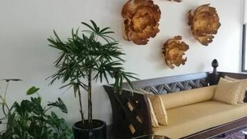 Una sala de estar con un sofá, una mesa de centro, una planta en maceta y adornos en la pared.