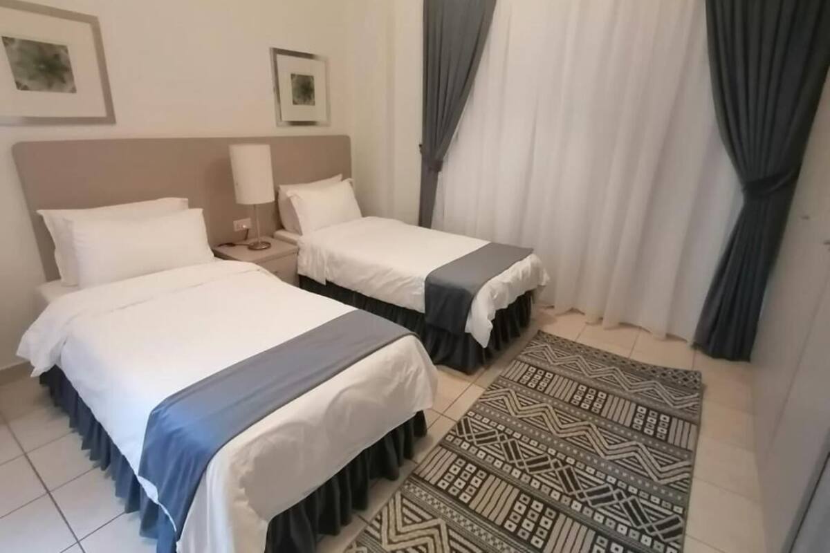 Habitación de hotel con dos camas, una alfombra estampada y cortinas.