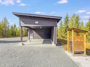 Un bâtiment doté d’une entrée couverte et d’une petite structure en bois située sur la droite.