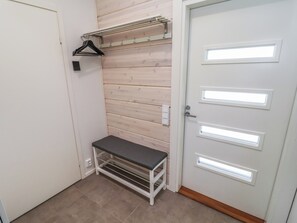 Ein Zimmer mit einer Bank, einem Kleiderständer und einer Tür mit beleuchteten Feldern.