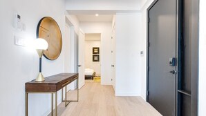 Un pasillo con una consola de madera, un espejo redondo y una puerta moderna.