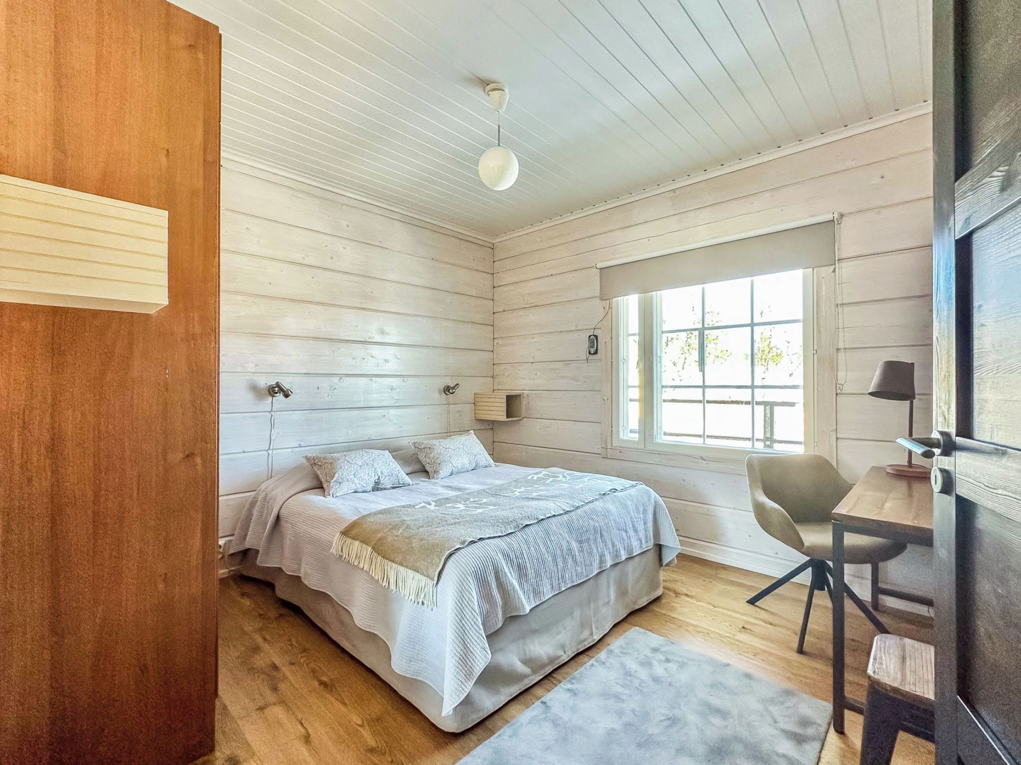 A bedroom with a bed, bedside table, chair, and a window.