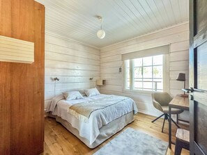 Une chambre à coucher avec un lit, une table de chevet, une chaise et une fenêtre.