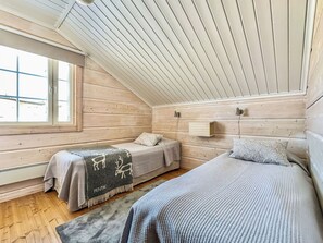 Une chambre avec deux lits, une fenêtre et un plafond en bois.
