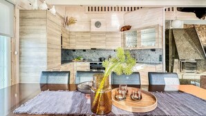 Une cuisine moderne avec des meubles en bois, un pare-feu en pierre et un coin repas avec une table en bois, mise pour quatre personnes.
