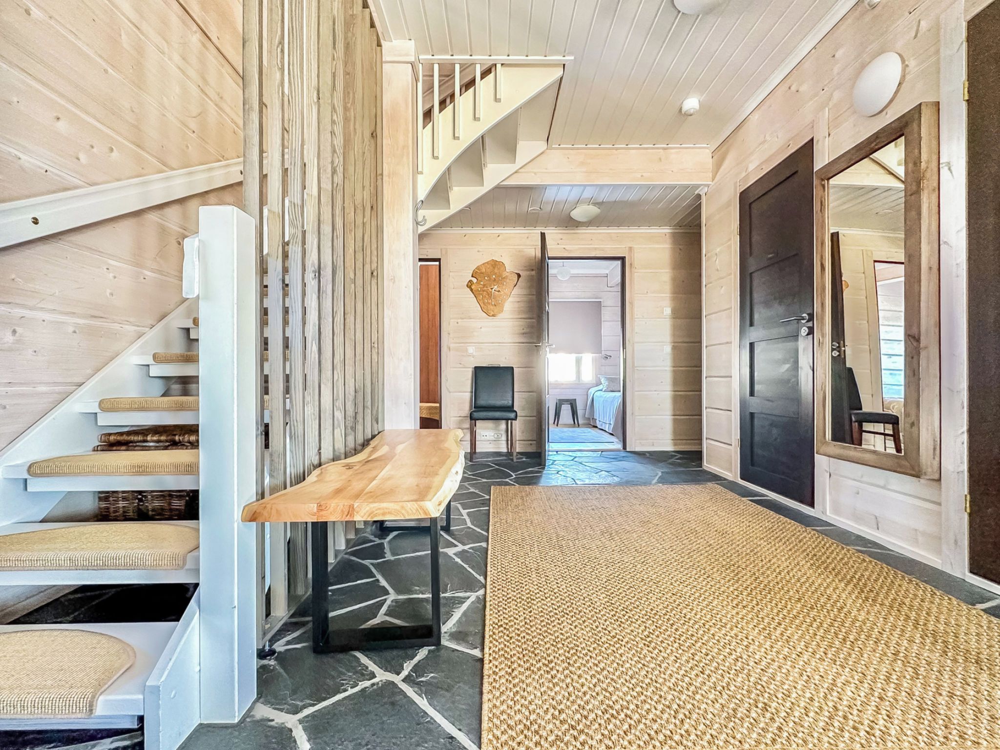 A modern interior with a staircase, a wooden table, and a rug.