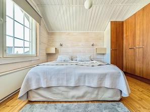Une chambre à coucher avec un lit, des murs en bois, une fenêtre et une armoire.