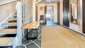 Un intérieur moderne avec un escalier en bois, une table centrale et une vue sur une chambre à coucher.