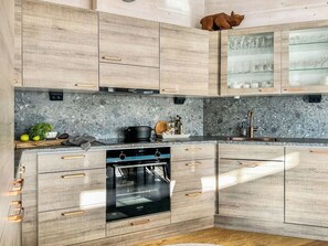 Een keuken met houten kastjes, een inbouwoven en een granieten aanrechtblad.