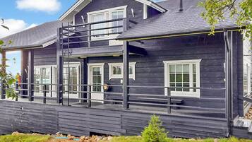 A two-story wooden house with a balcony and a covered porch area.