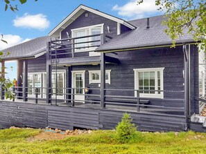 Een houten huis met twee verdiepingen, een balkon en een overdekte veranda.