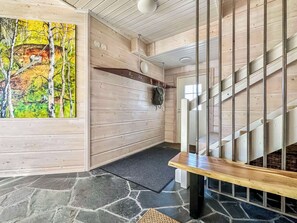 Un intérieur en bois avec un escalier, un tableau et un sol en pierre.