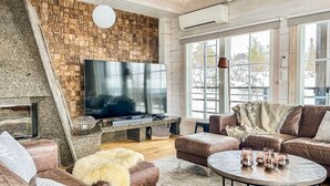 Un salon chaleureux avec une cheminée, un grand téléviseur, des canapés en cuir et une table basse.
