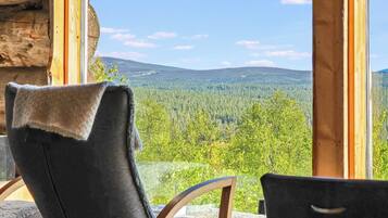 A room with a view of a forested landscape through large windows.