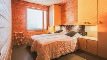 Une pièce chaleureuse en bois, avec un lit, une fenêtre et une table de chevet.