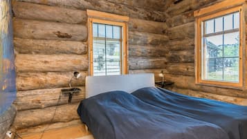 A log cabin bedroom with a bed, two bedside tables, and a window.
