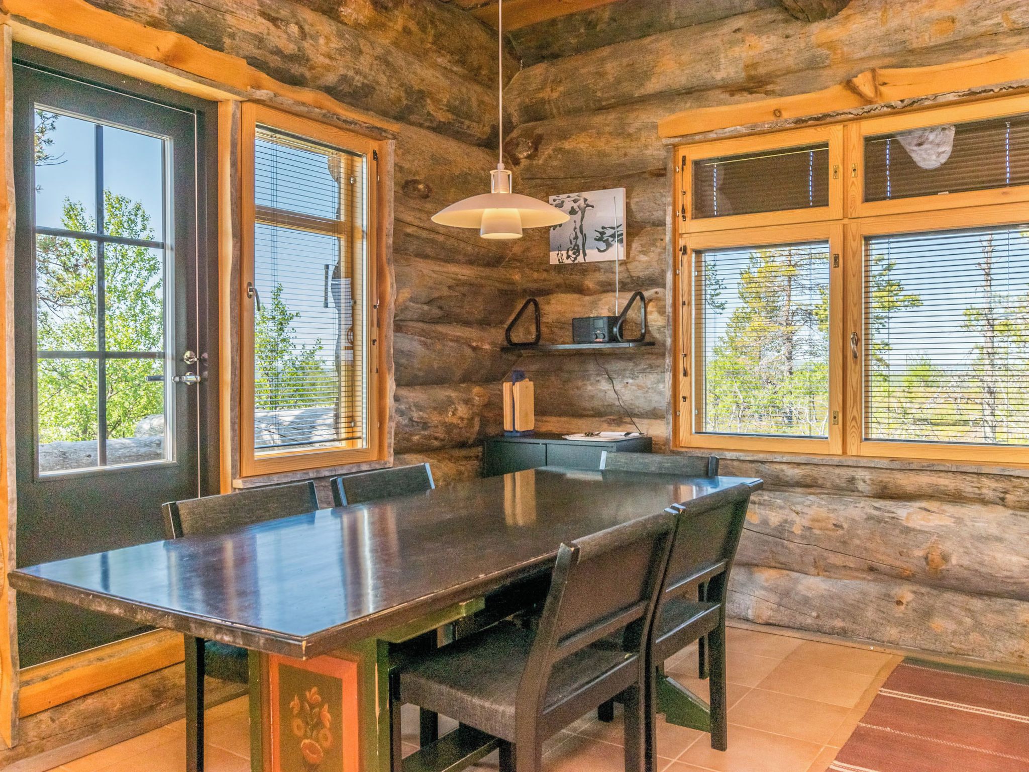 A rustic wooden interior with a dining table, chairs, and a hanging light fixture.