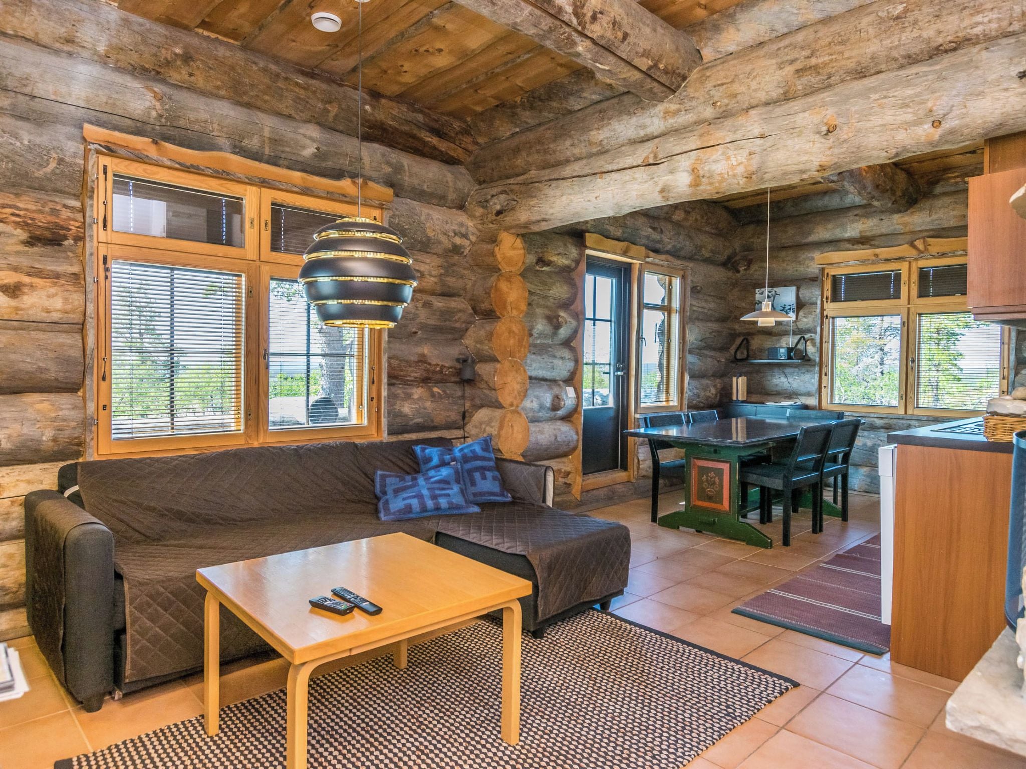 A log cabin interior with a sofa, table, and kitchen area.