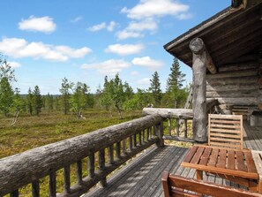 A wooden deck with a railing, a bench, and a table.