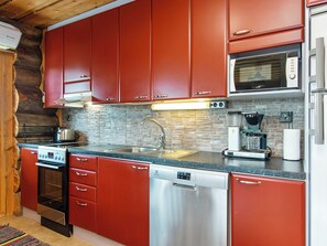A kitchen with red cabinets, a stainless steel dishwasher, and a microwave.