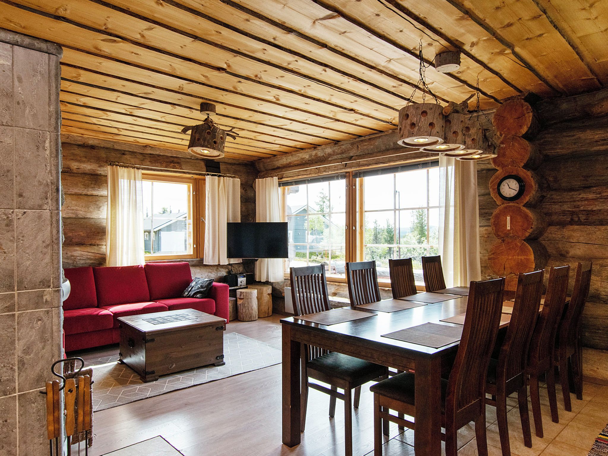 Een vakantiehuisje van binnen, met een rode bank, een houten eettafel en stoelen.