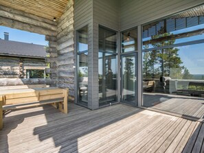 Eine Holzterrasse mit einer Bank und Glastüren zu einem Außenbereich.