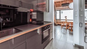 Eine moderne Küche mit Edelstahlgeräten, einer Holzarbeitsplatte und Blick auf einen Essbereich mit Holztisch und Stühlen.