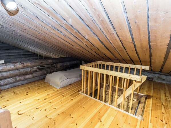 Quarto de sótão com estrutura de madeira, beliche e teto inclinado.