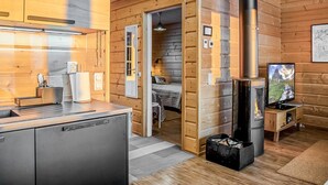 A cozy cabin interior with a kitchen area, a sleeping area, and a fireplace.