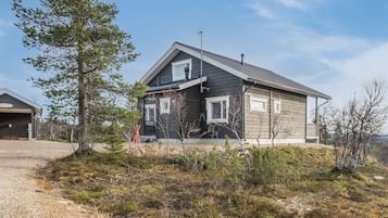 Kaksikerroksinen talo, jossa on tumma julkisivu, kalteva katto ja savupiippu.