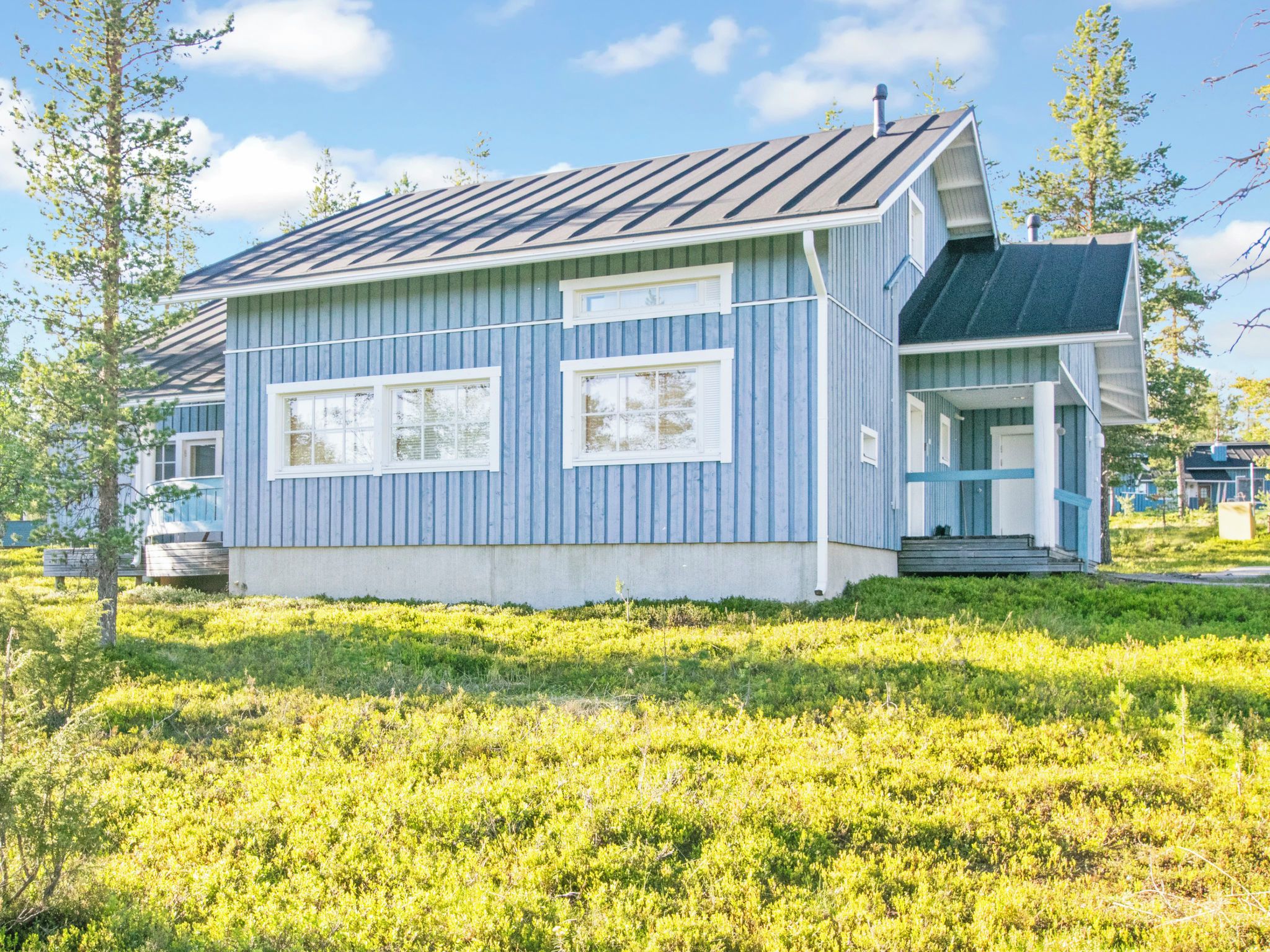 A single-story building with a sloped roof, a front porch, and a small deck.
