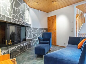 Un salon chaleureux avec une cheminée en pierre, une porte en bois et un escalier.