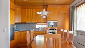 Une cuisine moderne avec des meubles en bois, un îlot central et un coin repas avec des chaises.