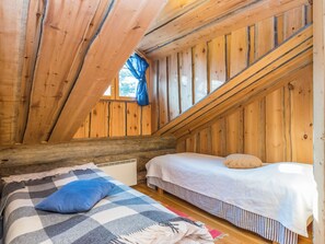 A cozy attic bedroom with wooden walls, a sloped ceiling, and two beds with bedding. - Kiela 1 by Interhome (Inari)