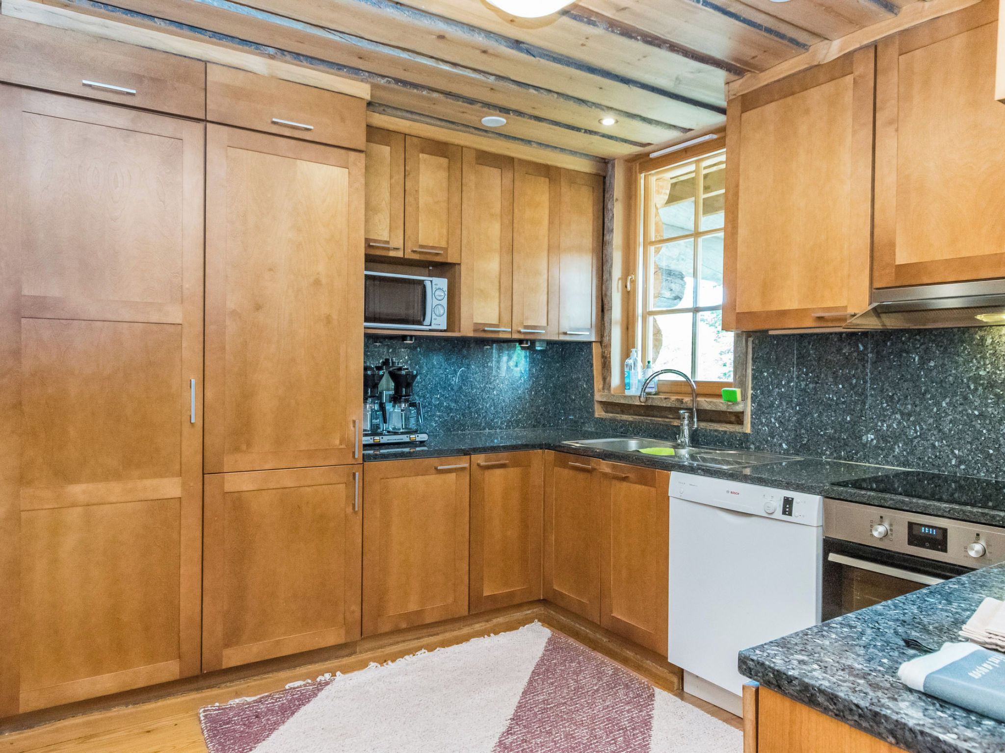 A kitchen with wooden cabinets, a microwave, a sink, and a dishwasher.
